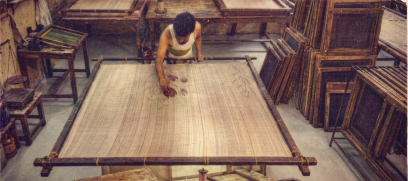Person working on a large woven mat in a workshop setting